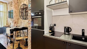 Ett modernt kök med en tegelvägg, en svart ugn, en kaffemaskin och en diskho.