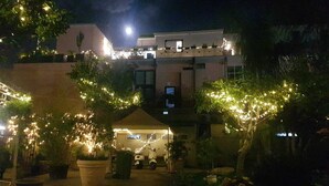 Un cortile con luci a tendina, un gazebo e un edificio con balconi.