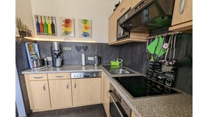 A kitchen with wooden cabinets, a built-in stove, a coffee maker, and various kitchen utensils. - Strandnaher Bungalow in Dornumersiel (Dornum)