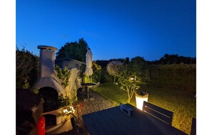 A patio with a grill, a table, and a small garden area. - Strandnaher Bungalow in Dornumersiel (Dornum)