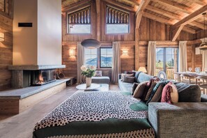 A spacious living room with a fireplace, a sofa set, and a dining area with a table and chairs. - Chalet de l'Emey - A Lifestyle with a View of Mont Blanc (12 people) (Saint-Gervais-les-Bains)