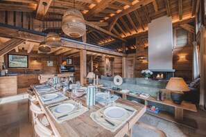 A spacious wooden interior with a dining area set for a meal, a fireplace, and a staircase leading to an upper level. - Chalet de l'Emey - A Lifestyle with a View of Mont Blanc (12 people) (Saint-Gervais-les-Bains)