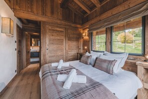 A wooden cabin bedroom with a large bed, a window with a view of the outdoors, and a wooden ceiling. - Chalet de l'Emey - A Lifestyle with a View of Mont Blanc (12 people) (Saint-Gervais-les-Bains)