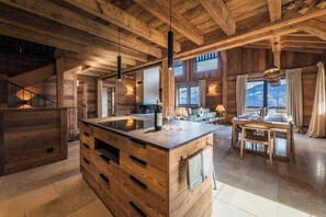 A spacious kitchen with a central island, wooden beams on the ceiling, and a view of mountains through large windows. - Chalet de l'Emey - A Lifestyle with a View of Mont Blanc (12 people) (Saint-Gervais-les-Bains)