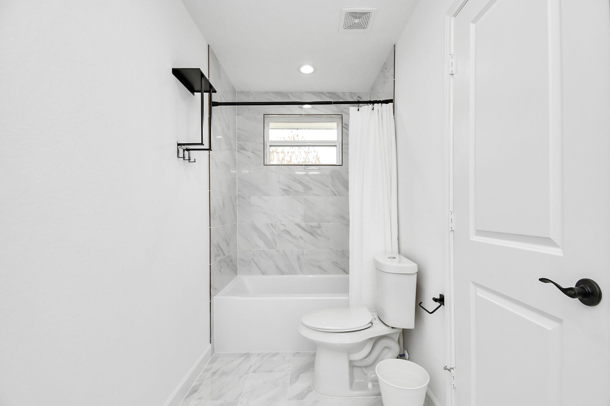 A modern bathroom with a bathtub, toilet, and shower curtain.