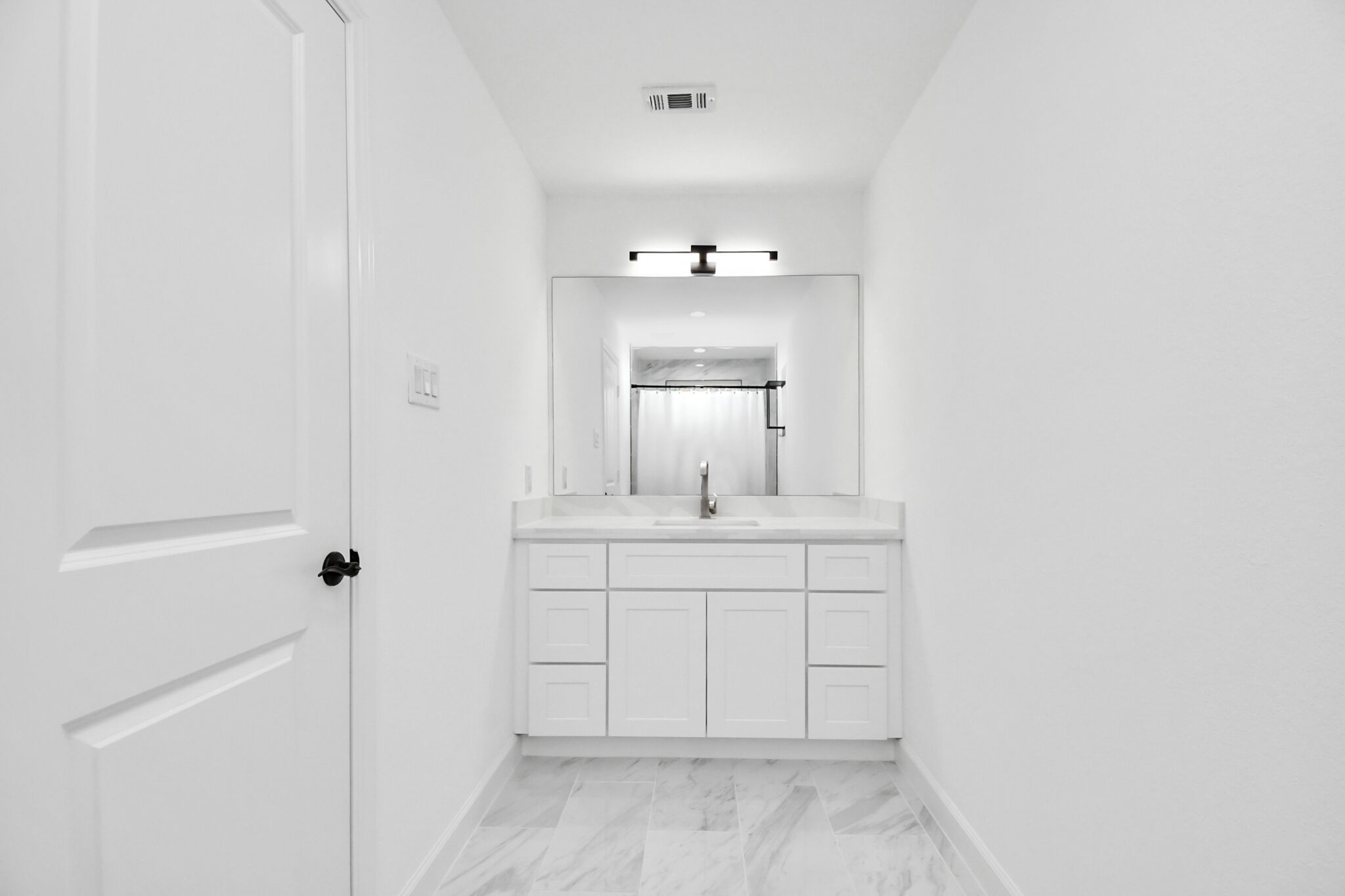 Un baño moderno con muebles blancos, un lavamanos y un espejo.