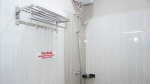 Ducha con barandilla, toallero adherido a la pared y cartel que indica prohibido fumar.