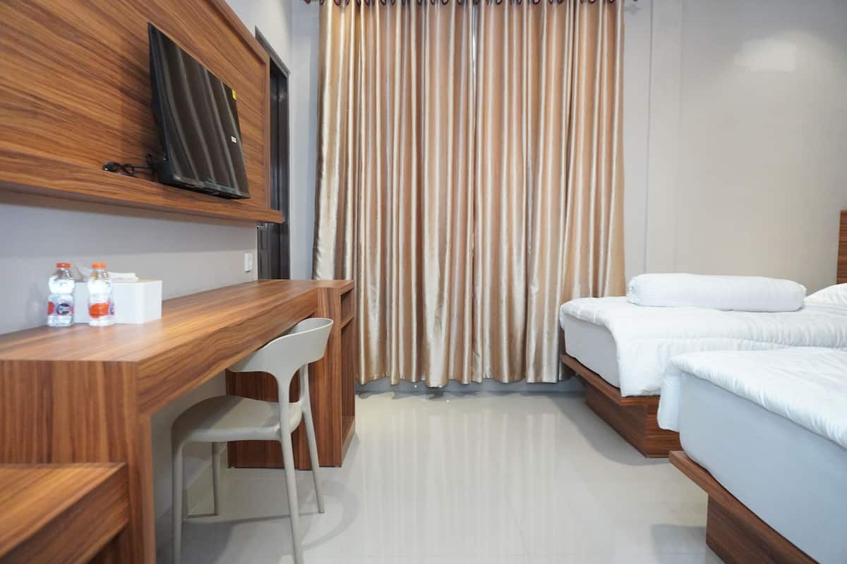 Une chambre d’hôtel avec un bureau en bois, une télévision, un lit et un rideau.