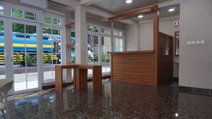 Un área de recepción con un mostrador de madera, ventanas amplias y un piso de mármol pulido.