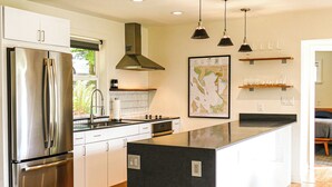 Una cocina moderna con electrodomésticos de acero inoxidable, una isla negra, iluminación colgante y un mapa en la pared.