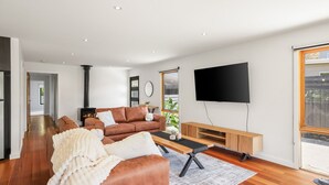 Een moderne woonkamer met een bank, salontafel en televisie. Er is een open haard en een raam met uitzicht.