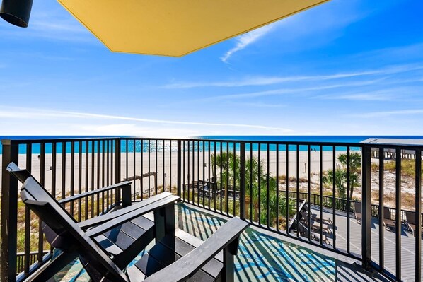 A balcony with a view of the beach, outdoor seating, and a pool area. - Beachfront Gulf Views | Beach Chairs Service + Pools (Panama City Beach)