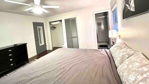 A bedroom with a bed, a ceiling fan, a wardrobe, and a door leading to a bathroom.