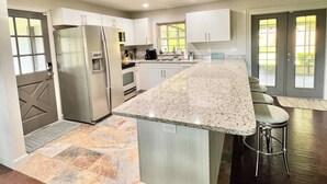 A modern kitchen with a central island, stainless steel appliances, and a large window.