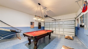 A pool table in a room with a garage door, a ceiling fan, and an American flag. - Spacious 5 bedroom Florida villa (Davenport)