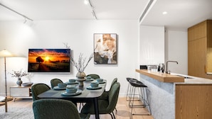 A modern dining area with a table set for four, a bar counter, and a kitchen area. - Stylish 3-bed Townhouse in Vibrant Fitzroy (Melbourne)