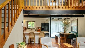 Une cuisine moderne avec des meubles en bois, un coin repas avec une table et des chaises en bois, et un escalier avec des rampes en bois.