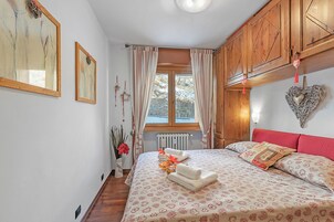 A bedroom with a bed, wooden cabinets, a window with curtains, and wall art.