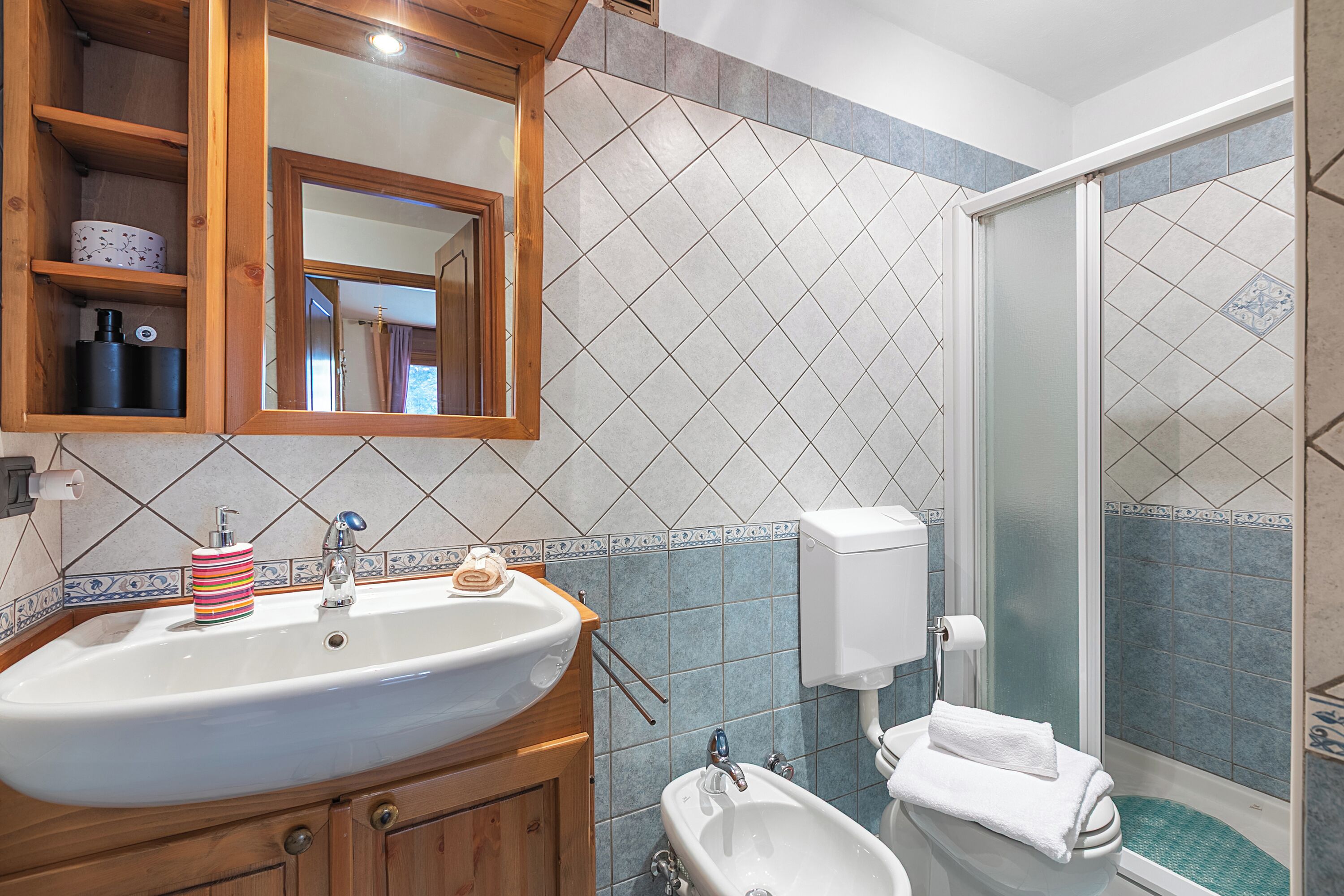 A bathroom with a sink, mirror, and shower.