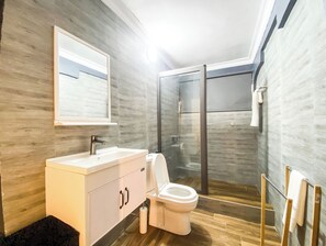 Ein modernes Badezimmer mit einem weißen Waschtisch, einer Toilette und einer Duschkabine.