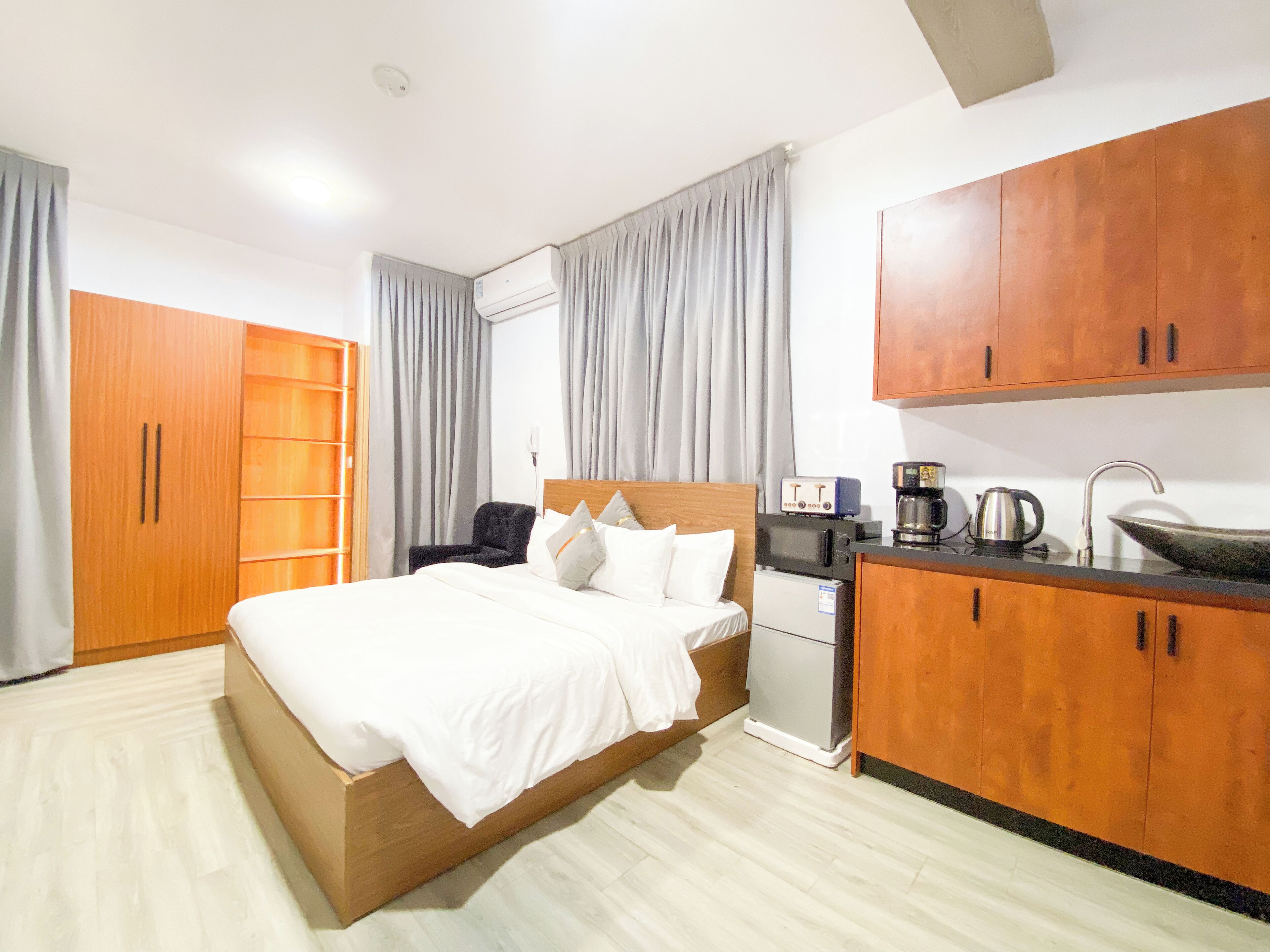 Una camera d'albergo con un letto, una scrivania, angolo cottura e mobili in legno.