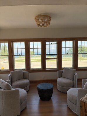 A room with a view of a golf course, large windows, and a central round table. - Lake house North Beach lake breezes, morning sunrises and evening sunsets (Racine)