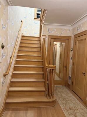 A wooden staircase with a handrail, carpeted floor, and floral wallpaper. - Lake house North Beach lake breezes, morning sunrises and evening sunsets (Racine)