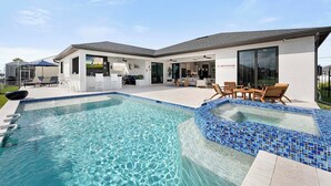 Et moderne hus med swimmingpool, udendørs siddepladser og en patio.