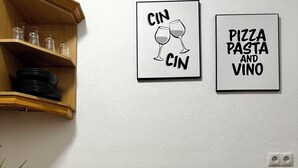 Une cuisine avec des étagères en bois, une chaise noire et deux panneaux encadrés accrochés au mur.