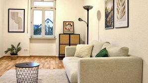 Un salon comprenant un canapé, une petite table ronde, un lampadaire et des œuvres d’art accrochées aux murs.