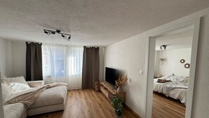 Una sala de estar moderna con un sofá, un televisor y piso de madera.