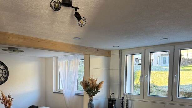 Una cocina moderna con una isla central, muebles blancos y piso de madera.