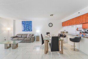 Un salon moderne avec une table basse en verre, un canapé et un coin repas comprenant des chaises et une table.