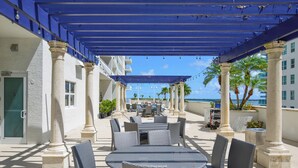 An outdoor patio with tables and chairs, columns, and a blue pergola. - Brickell Bay 2308 (Miami)