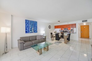 Un salon moderne avec une table basse en verre, un canapé et un coin repas avec des chaises.