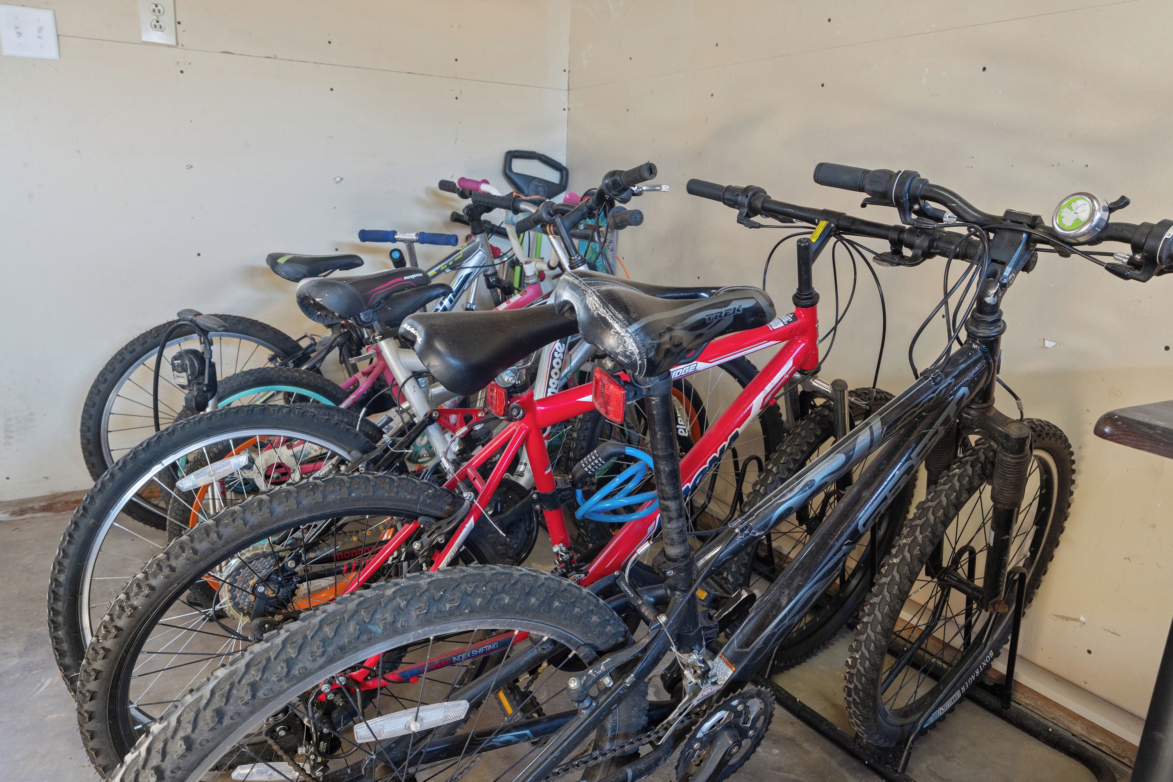 A row of bicycles parked against a wall in a room with a concrete floor.