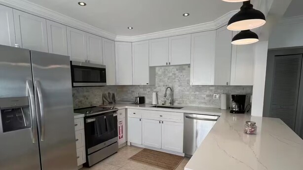 A modern kitchen with white cabinets, stainless steel appliances, a marble countertop, and pendant lighting. - 2BR/1B - Sunny Hollywood Hideaway (Hollywood)
