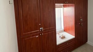A room with a large wooden wardrobe, a small window with blinds, and a tiled floor. - 2BR/1B - Sunny Hollywood Hideaway (Hollywood)