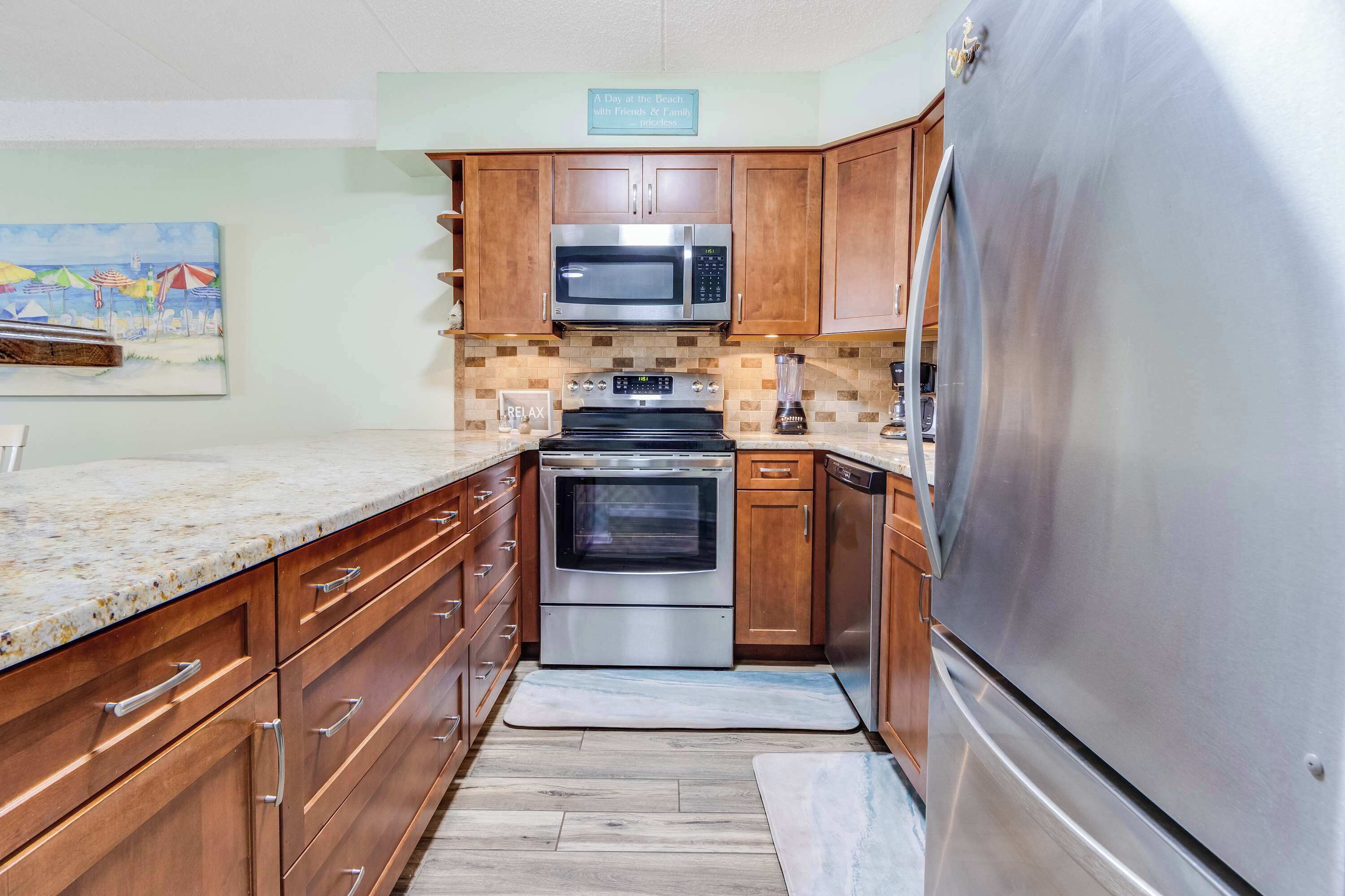 A kitchen with wooden cabinets, stainless steel appliances, and a beach-themed wall art.