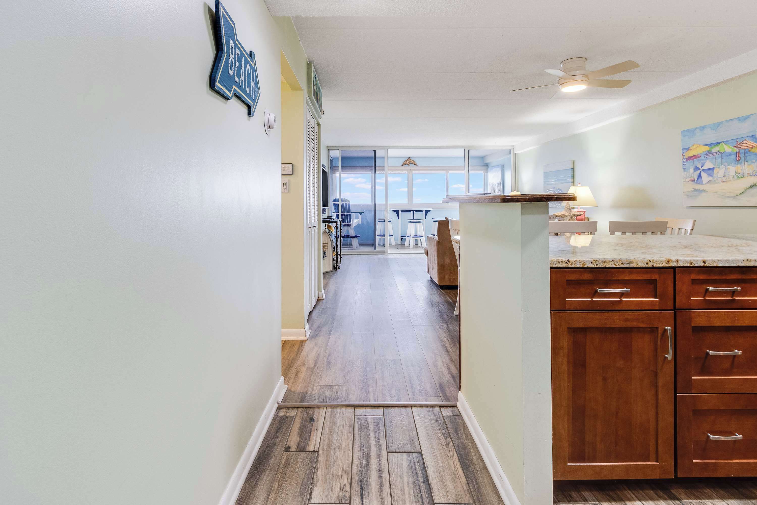 A kitchen with wooden cabinets, a countertop, and a view to the outside.