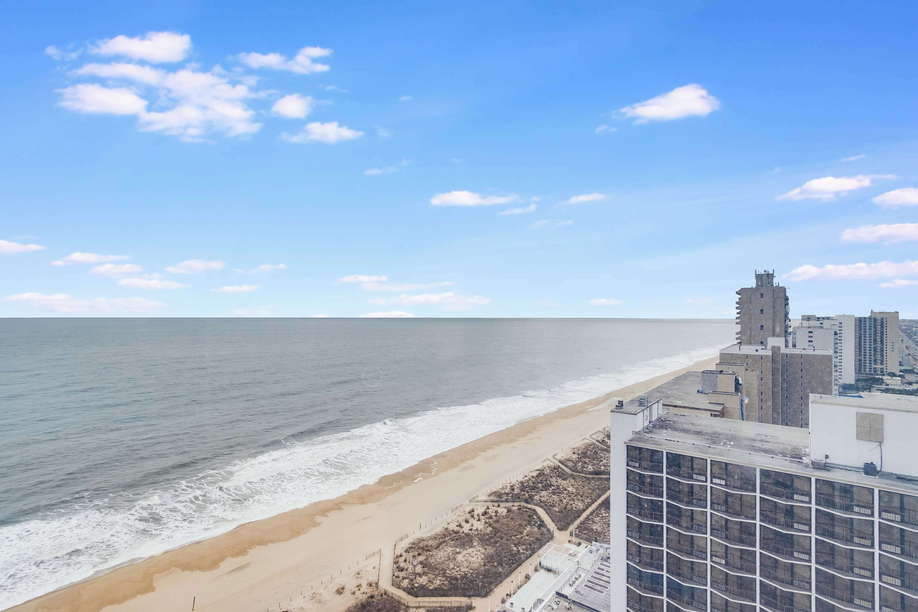 A coastal cityscape with a beach, buildings, and a clear sky.