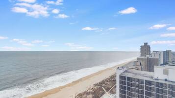A coastal cityscape with a beach, buildings, and a clear sky.