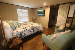 Ein Schlafzimmer mit einem Bett, einem Schreibtisch, einem Stuhl, einem Fernseher und einer Tür.