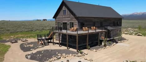 A rustic cabin with a large deck, surrounded by a natural landscape.