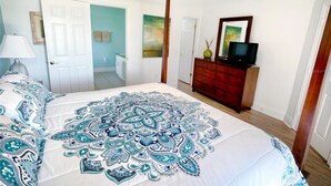 Een slaapkamer met een groot bed, een dressoir, een televisie en een plafondventilator.