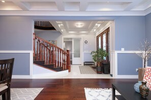 A spacious living area with a wooden staircase, a potted plant, and a bench. - Sunny Luxury Home Mountain View & Central Lonsdale (North Vancouver)