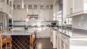 Une cuisine moderne avec des meubles blancs, un plan de travail en marbre et des appareils électroménagers en acier inoxydable.