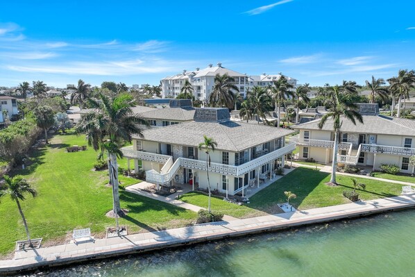 A coastal property with a large house featuring a balcony, a pool, and a view of the water. - Villa de Marco, cozy water-front 1-bedroom condo on Marco Island Florida (Marco Island)