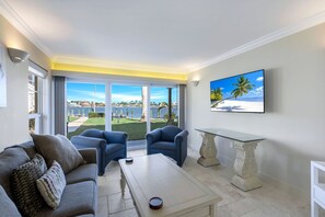 A modern living room with a sofa, two armchairs, a coffee table, and a TV mounted on the wall. - Villa de Marco, cozy water-front 1-bedroom condo on Marco Island Florida (Marco Island)