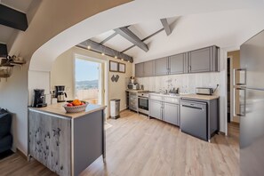 A modern kitchen with grey cabinets, a central island, and a view of the outdoors. - SUPERB "TOP OF VILLA" APARTMENT, PANORAMIC SEA VIEW, SWIMMING POOL (Le Lavandou)
